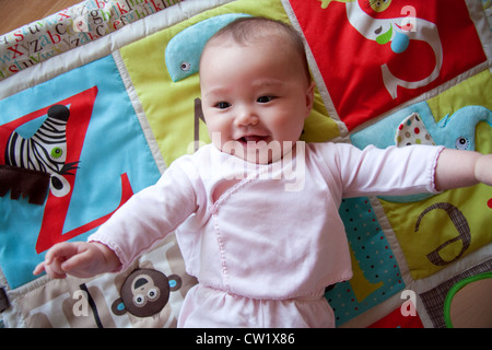 Happy baby on colorful playmat Stock Photo