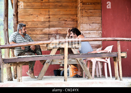 two men drinking coffee and talking sitting at a table in a rustic cafe in Cyprus Stock Photo