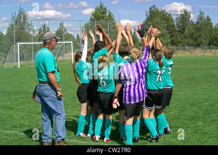 Young girls raise their hands in the air for a 'high five' team salute at the start of an after-school soccer match in Bend, Oregon, USA. Stock Photo