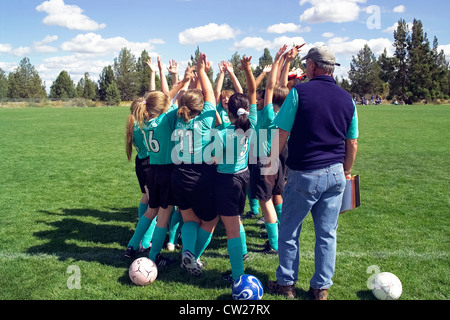 Young girls raise their hands in the air for a 'high five' team salute at the start of an after-school soccer match in Bend, Oregon, USA. Stock Photo