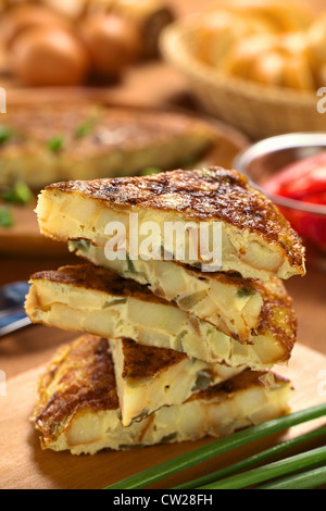 Fresh homemade Spanish tortilla (omelett with potatoes and onions) slices piled on wooden cutting board Stock Photo
