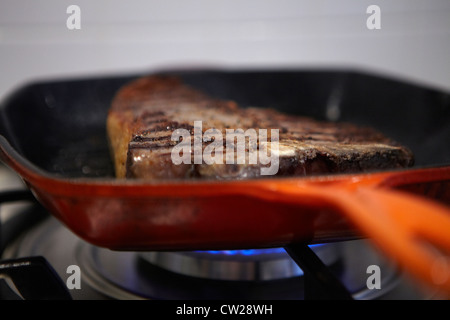 T-bone steak in frying pan getting cooked Stock Photo