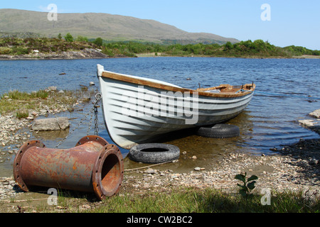 Old boat with a strange anchor, in a quiet lake in Ireland Stock Photo