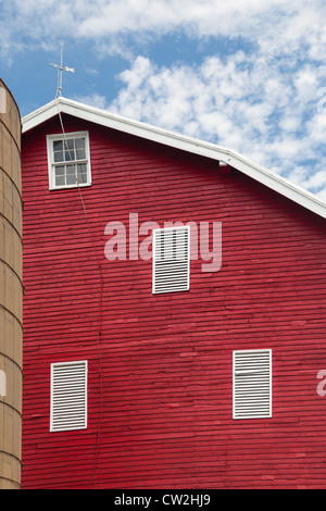 Red painted wooden barn with white door on farm in traditional American / US style Stock Photo