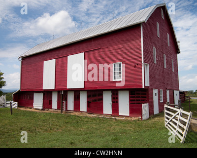 Red painted wooden barn with white door on farm in traditional US style Stock Photo