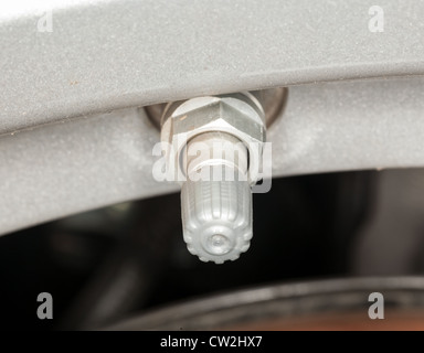 Silver colored tyre pressure valve on alloy wheel of car Stock Photo