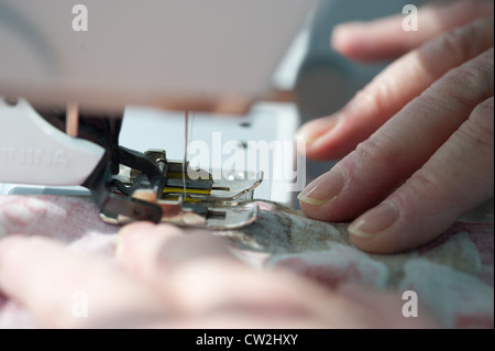 Hands moving fabric through sewing machine  Stock Photo
