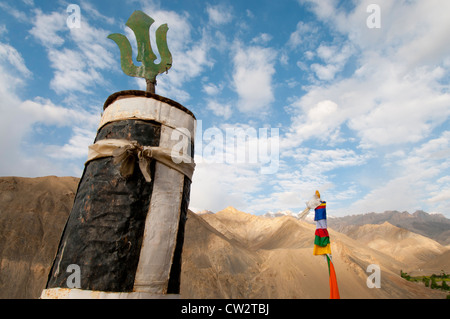 Prayer pole and pole covered in prayer flags set against brown mountains at Lamayuru Monastery in Ladakh, India Stock Photo