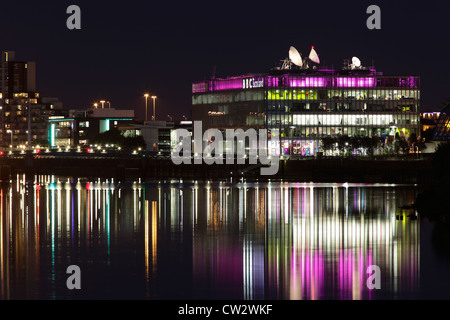 Looking East towards the illuminated BBC Scotland Headquarters on Pacific Quay reflected in the River Clyde at night, Glasgow, Scotland, UK Stock Photo