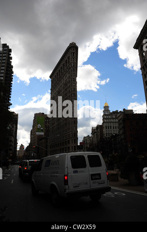 Blue sky grey clouds silhouette view Flatiron Building and Sohmer Piano Building, rising above white van on Broadway, New York Stock Photo