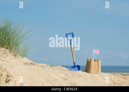 Union Jack flag in a sandcastle next to a childrens spade on a sand dune. Wells next the sea. Norfolk, England Stock Photo