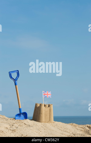 Union Jack flag in a sandcastle next to a childrens spade on a sand dune. Wells next the sea. Norfolk, England Stock Photo