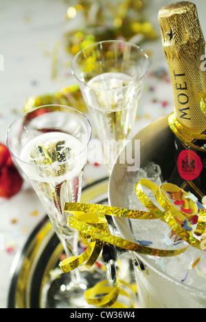 2 champagne glasses standing next to a radiator with a bottle of Moet Stock Photo