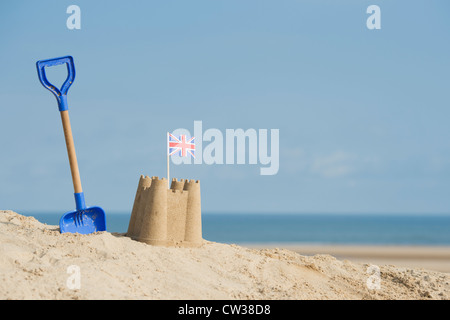 Union Jack flag in a sandcastle next to a childrens spade on a sand dune. Wells next the sea. Norfolk, England Stock Photo