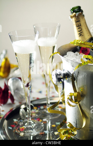 2 champagne glasses standing next to a radiator with a bottle of Moet Stock Photo