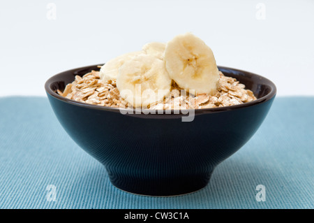 Rolled oats, or porridge oats with sliced banana on top in black bowl Stock Photo