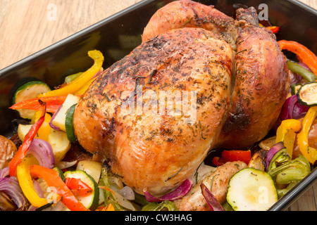A ready to eat freshly roasted chicken in an oven dish with roasted vegetables - studio shot Stock Photo