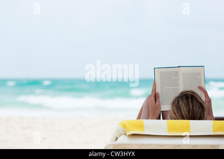 woman reading book and relaxing on beach at Playa del Carmen Stock Photo
