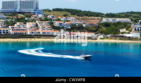 A speedboat turns and leaves the bay in arenal d'en castell menorca spain Stock Photo