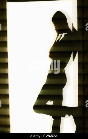 Silhouette of a man standing in a doorway and covering face with hands Stock Photo