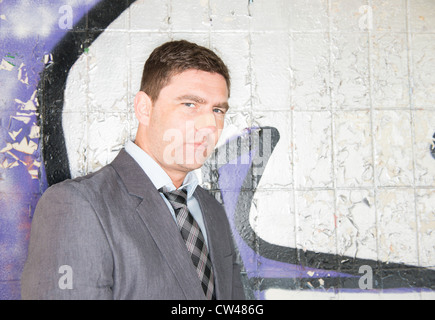 Businessman standing in front of wall covered with grafitti Stock Photo