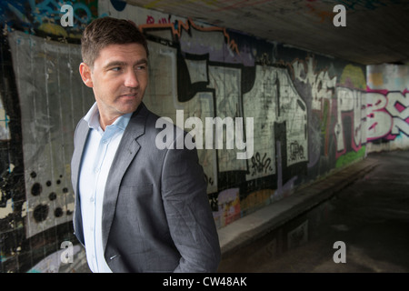 Man in a suit walking in underpass covered with grafitti Stock Photo