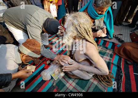 Sadhu (holy man) blessing pilgrims on the street during Kumbh Mela festival 2010, Haridwar, India. Stock Photo