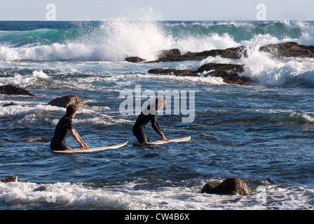 Two surfers going into the surf at Moses Rock beach, Western Australia Stock Photo