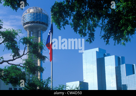 View of Reunion Tower and Hyatt Hotel in Dallas, TX through trees with state flag Stock Photo