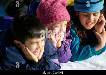 Close-up of two girls and a boy lying in the snow Stock Photo