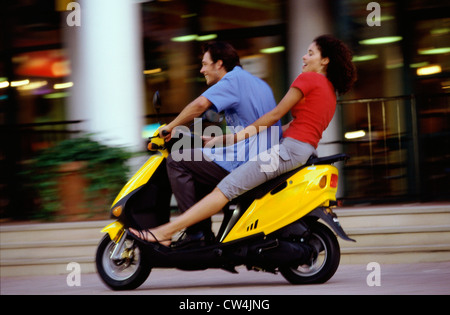 Side profile of a young couple riding a scooter Stock Photo