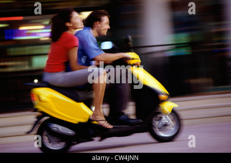 Side profile of a young couple riding a scooter Stock Photo