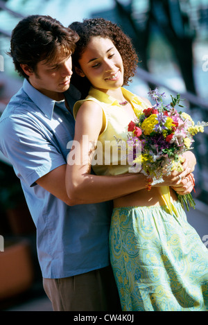 Young man embracing a teenage girl from behind Stock Photo
