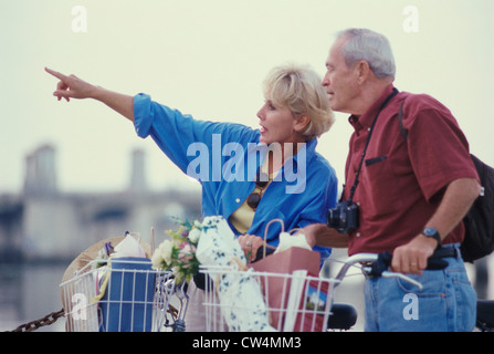 Senior couple standing with bicycles looking sideways Stock Photo