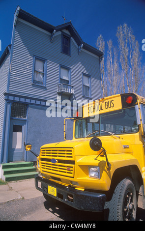 A yellow schoolbus outside of a wooden frame building, Port Wing, WI Stock Photo