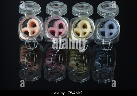 Yogurt pretzels in small canning jars sitting in a row on a black mirror. Reflection on glass Stock Photo