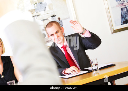 young business man raises his hand to vote during a heated business meeting Stock Photo