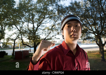 Portrait of young businessman with clenched fist at park Stock Photo