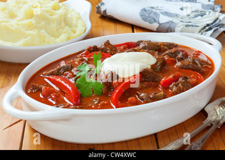 Goulash with red peppers and sour cream and a side dish of mashed potato. Stock Photo