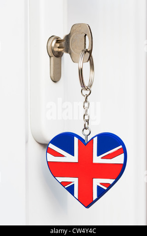 Key inserted into a door lock with a key ring in a heart shape Union Jack UK flag pattern - brightly lit Stock Photo