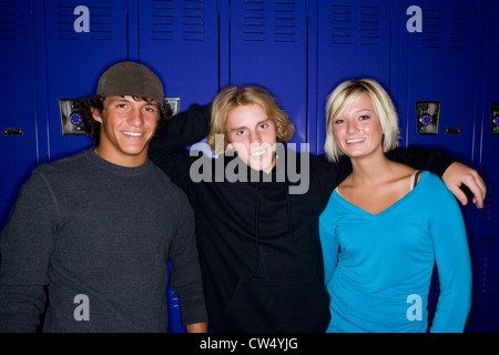 Portrait of cheerful students standing in front of lockers Stock Photo