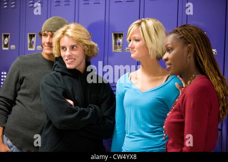 Cheerful students with female teacher standing by lockers and looking away Stock Photo