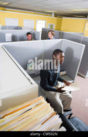 Businessman using headset while colleagues conversing in the background Stock Photo