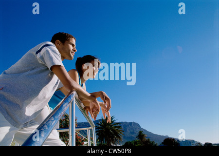 Low angle view of a young couple leaning against a railing Stock Photo