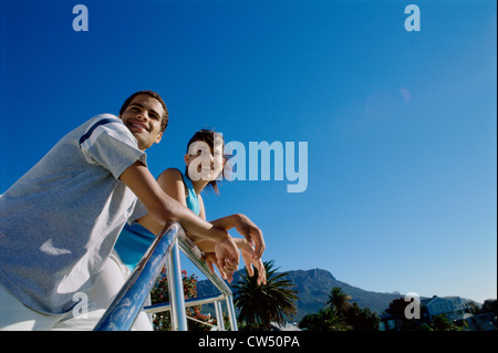 Low angle view of a young couple leaning against a railing Stock Photo