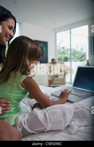 Side profile of a girl using a laptop with her mother Stock Photo