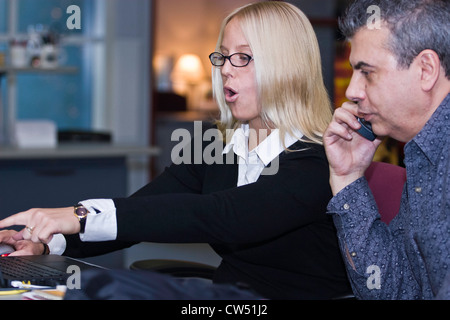 Business executives using a mobile phone and a laptop, Florida, USA Stock Photo