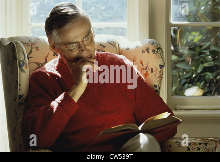 Close-up of a senior man sitting in an armchair and reading a book Stock Photo