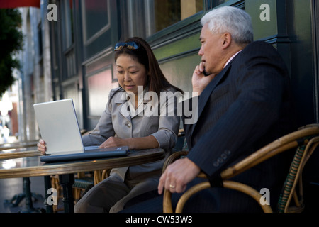 Businesswoman using a laptop with a businessman sitting beside her Stock Photo