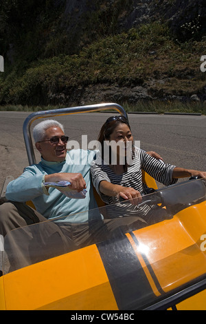 Mature woman driving a tourist car with a mature man sitting beside her and smiling Stock Photo